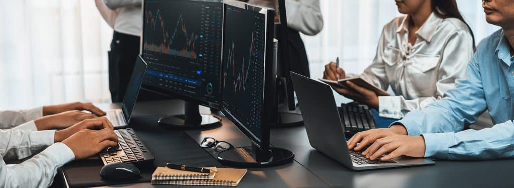 Group,Of,Traders,Discussing,On,Office,Desk,,Monitoring,Stock,Market